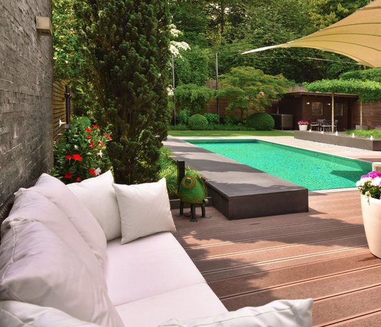 Ein Lounge-Garten mit weißer Outdoor-Couchgarnitur, Pool und Sonnensegel