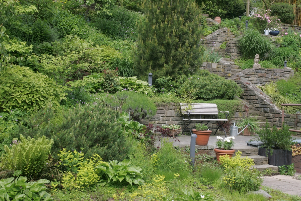 kleine Terrasse mit Sitzbank in einem Hanggarten mit mehreren Ebenen